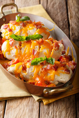 Homemade chicken breast with bacon, tomatoes, cheddar cheese and basil close-up in a copper pan. vertical