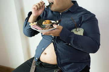 fat man eating, portrait of overweight person feels hungry and eating chips,cake,green tea frappe seated on armchai, isolated on white background with clipping path
