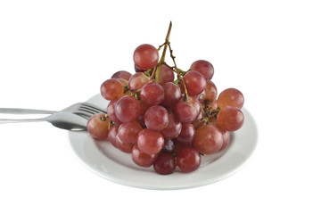 fresh red grapes fruit with spoon and fork in dish isolated on over white background.