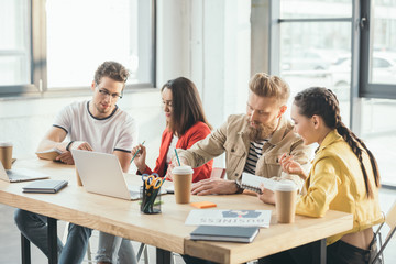 Successful business people working together by the table with laptops in modern light office