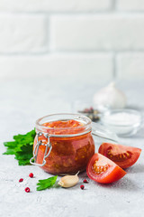 Homemade roasted garlic marinara tomato sauce in glass jar on concrete background. Selective focus, space for text.