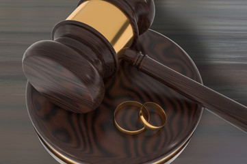 Divorce concept with wooden gavel and gold wedding rings