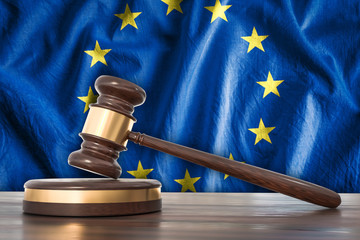 Wooden gavel and flag of EU on background - law concept