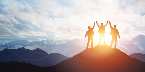 Silhouette of the team on the peak of mountain