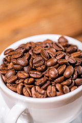 Coffee beans in white cup on old wooden table. Vintage style