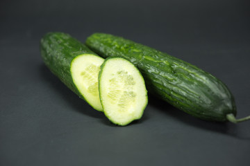 cucumber, whole cucumber and pieces of cucumber on a black background. Black paper, macro