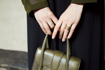 Green shirt and black dress, with green leather handbag, on gray concrete background. Fashion and stylish concept.