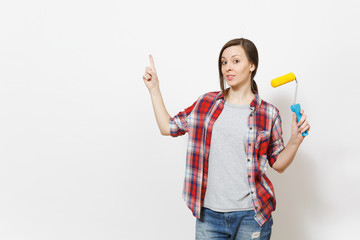 Young concerned woman holding paint roller for wall painting and pointing index finger up on copy space isolated on white background. Instruments for renovation apartment room. Repair home concept.