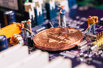 miniature worker dig gold bitcoin miner on electronic circuit board