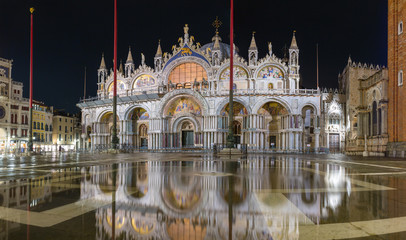 Fototapeta na wymiar Basilica in San Marco square in Venice with reflection at night during the high tide, or aqua alta, that flooded the square with sea water