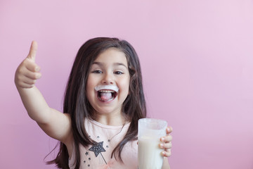 Happy child girl drinking yogurt. Whiskers from yogurt.