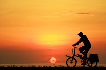Fototapeta na wymiar Silhouette man and bike relaxing on sunrise