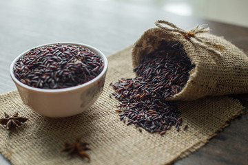 Healthy food background : Raw Rice berry in a white bowl and pouring by a bag  on the wooden table.