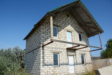 Building house construction with white brick, balcony, attic.