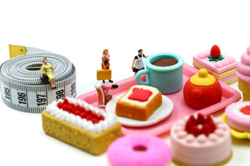 Miniature people : Beautiful womans and sweet dessert with measuring tape,concept of healthy lifestyles and nutrition.