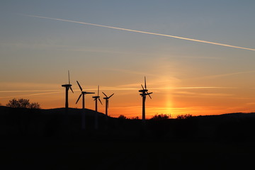 Fototapeta na wymiar Wind power station in the sunset. Rotating blades of energy generators. Ecologically clean electricity. Modern technologies for the use of natural resources.