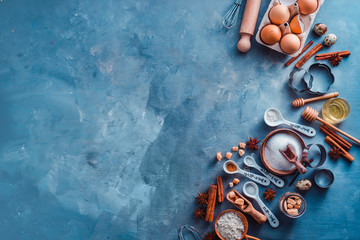 Baking utensils header. Measuring spoons, sea salt, eggs, flour, oil and sugar with whisks and cookie cutters on a modern concrete background with copy space. Making pastry concept.