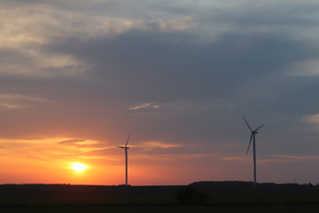 Obraz premium Wind power station in the sunset. Rotating blades of energy generators. Ecologically clean electricity. Modern technologies for the use of natural resources.