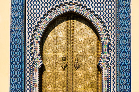 Brass gate and zellige mosaic floral tilework on doorway of traditional Moroccan building