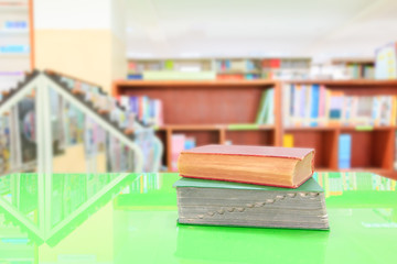 old book and heap treatise in school library on table green. blurry bookshelves background. education learning concept with copy space add text