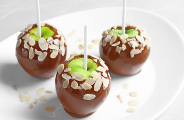 Plate with delicious caramel apples on light background