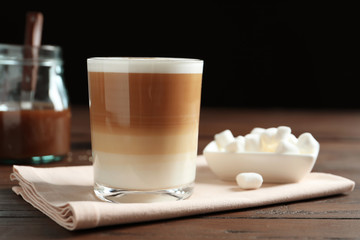 Glass with delicious caramel latte on table