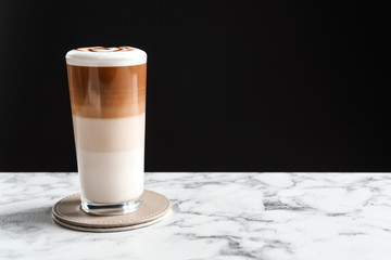 Glass with delicious caramel latte on table