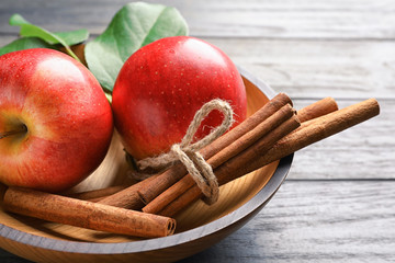 Fresh apples and cinnamon sticks in bowl, closeup