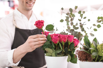 Male florist making beautiful bouquet in flower shop, closeup