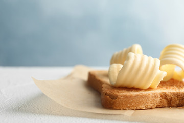 Toasted bread with fresh butter curls on table, closeup - obrazy, fototapety, plakaty