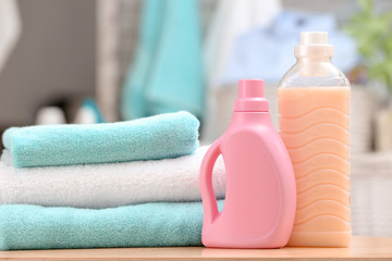 Stack of clean towels and bottles with detergent on table