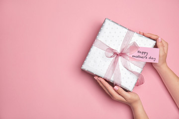 Woman holding elegant gift box for Mother's Day on color background, top view