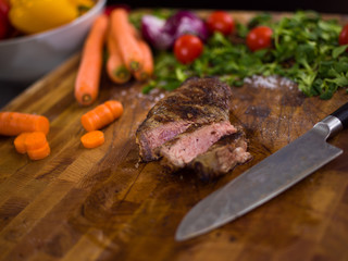 Juicy slices of grilled steak on wooden board