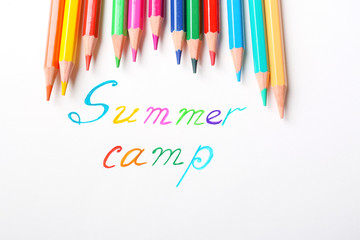Colorful pencils and words SUMMER CAMP on white background, top view