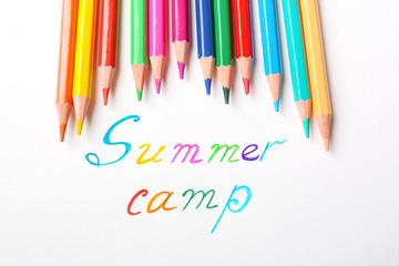 Colorful pencils and words SUMMER CAMP on white background, top view