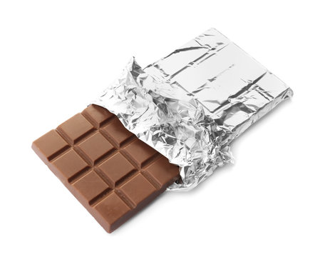 Delicious milk chocolate bar in foil on white background