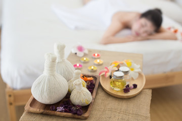 Fototapeta na wymiar Selective focus of Herbal compress balls with oil on the wooden table in spa salon and blurred background of woman lying on bed. alternative medicine and relaxation Concept.