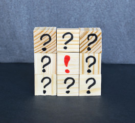 Many question marks written on wooden cubes on the dark background.