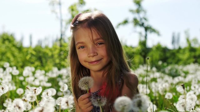 Portrait of a girl in the garden with dandelions. Slow motion.