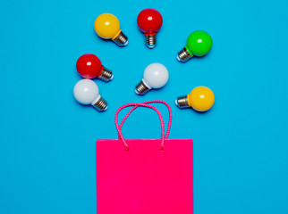 colored bulbs and shopping bag on blue background