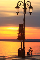 Obraz premium Lazise, tramonto sul lago di Garda con bicicletta