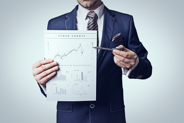 Businessman with pen holding stock chart on white background