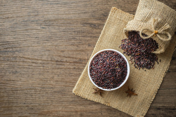 Healthy food background : Raw Rice berry in a white bowl and pouring by a bag  on the wooden table.
