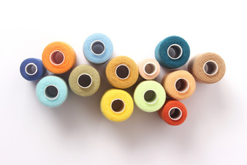 sewing thread of different colors isolated on white. top view 