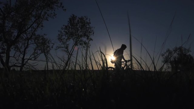A young man is actively spending time on his bike at sunset. A bike ride in the sunset