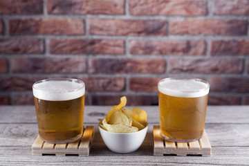 two glasses of beer on pallet with chips