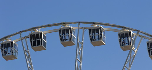 Wheel of view with cabins against the sky. Widescreen photo, fragment