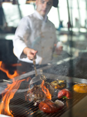 chef cooking steak with vegetables on a barbecue