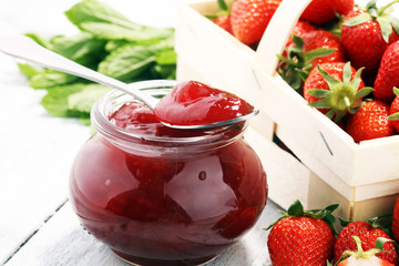 Strawberry jam in a jar and fresah strawberries.