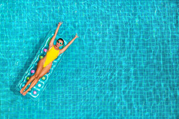 amazing beautiful girl in a yellow bikini air mattress swims in the pool of a luxury hotel, summer vacation, happiness, travel, smile joy, listening to music, drinking cocktail, top view - obrazy, fototapety, plakaty